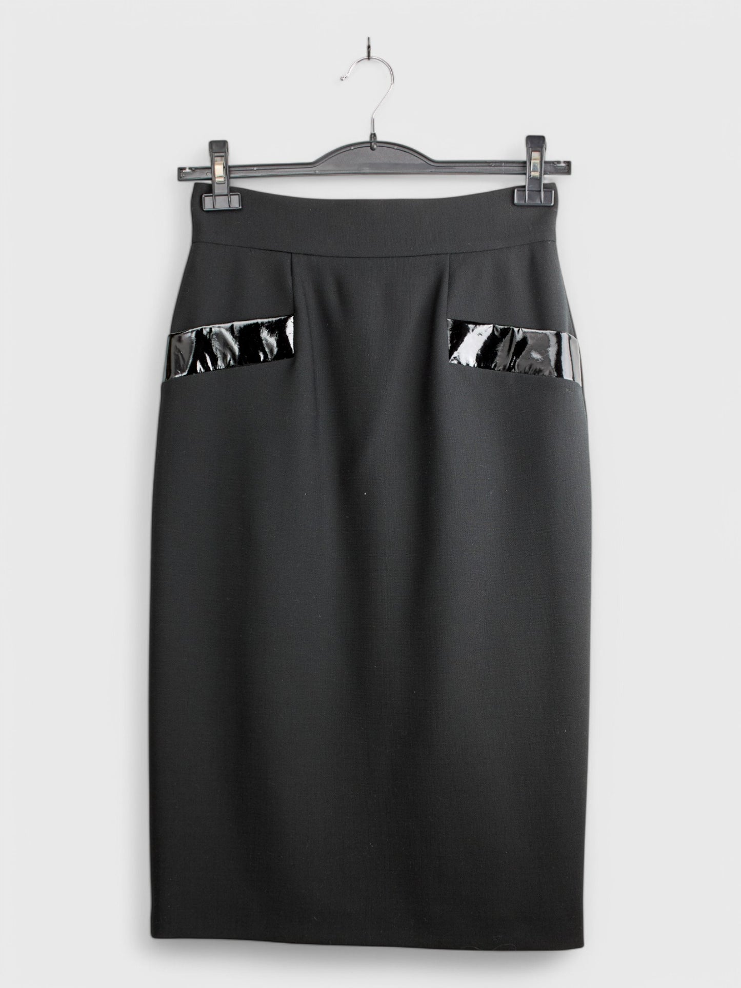 Black wool skirt with visible pockets on the sides, knee-length, displayed on a hanger against a white background.