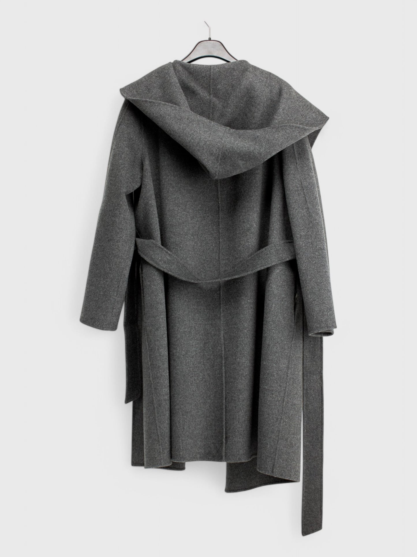 Back view of dark grey wool coat with hood and belted waist, mid-calf length, hanging on a hanger