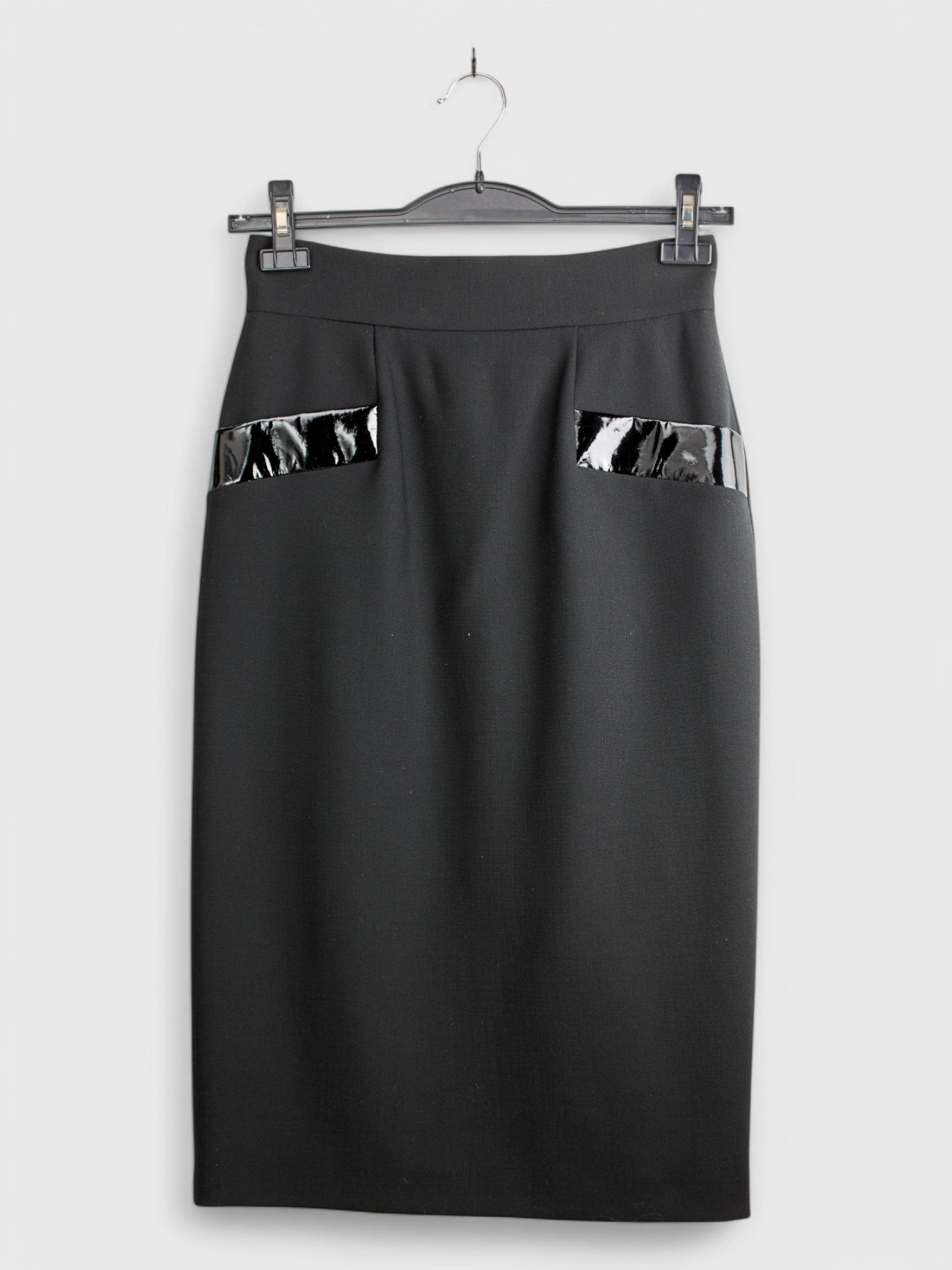 Black wool skirt with visible pockets on the sides, knee-length, displayed on a hanger against a white background.