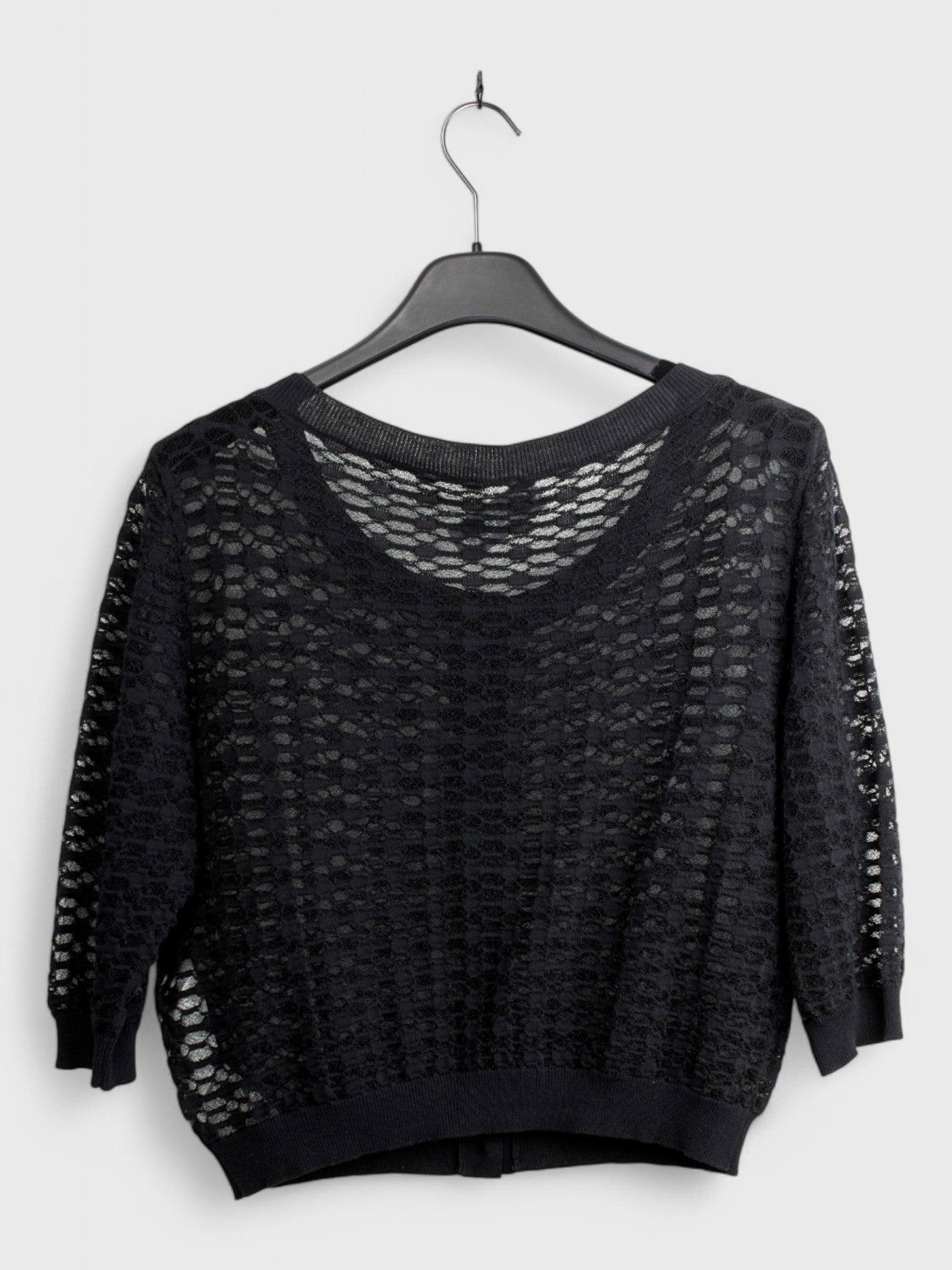 Back view of black knit cardigan with open texture pattern and long sleeves hanging on hanger, size 44